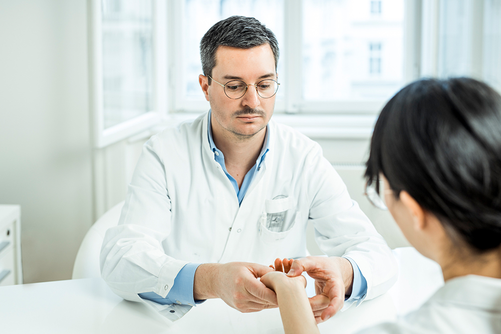 Dr. Figl behandelt Patientin an der Hand